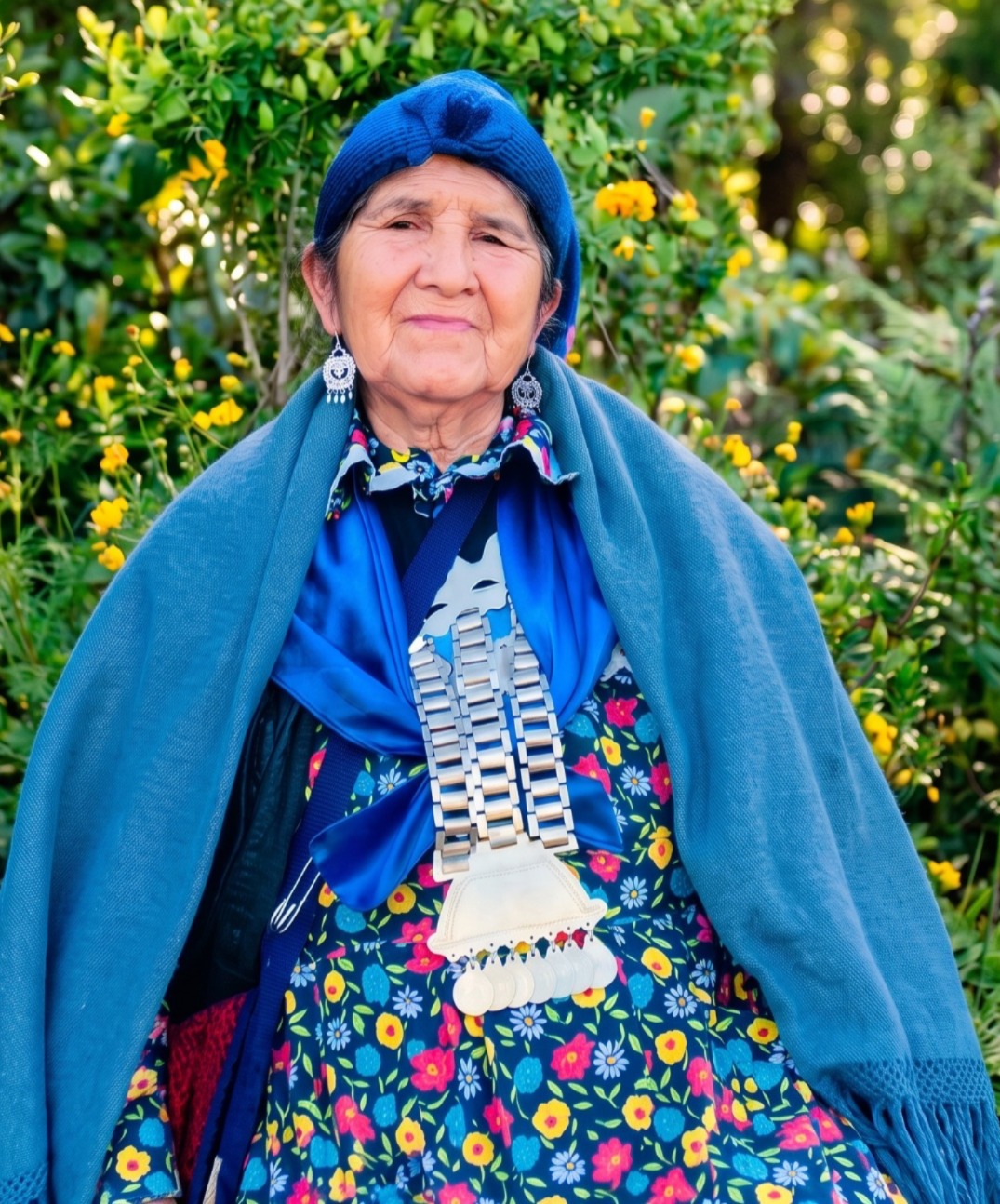 Mujer mapuche rodeada de flores y vegetación